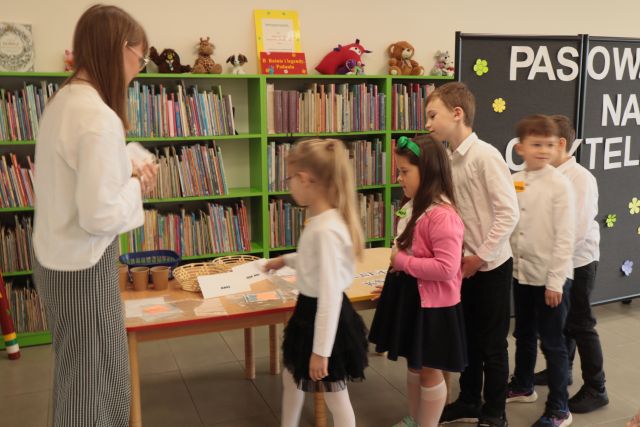 przedszkolaki stoją w kolejece przy stoliku