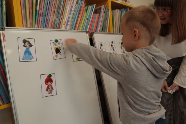 chłopiec przypina ilustrację do tablicy magnetycznej