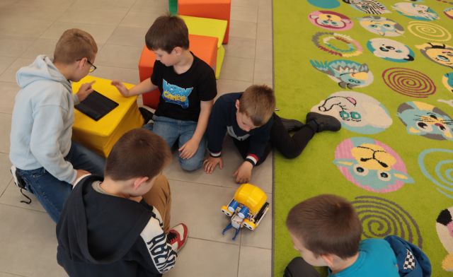 chłopcy na podłodze testują robota z klocków LEGO