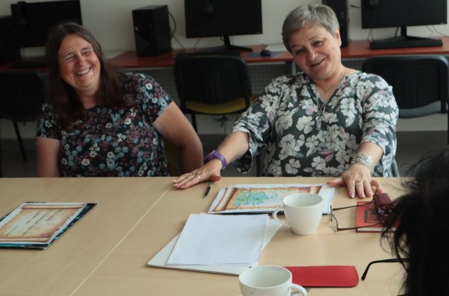 na zdjęciu dwie uśmiechnięte uczestniczki warsztatów, na stole kartki