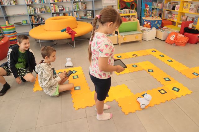 dzieci bawią się robotami jeżdżącymi po pomarańczowych puzlach