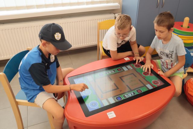 dzieci grają przy stoliku interaktywnym