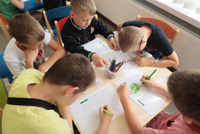 dzieci siedza przy stolijkach i rozkodowują obrazki
