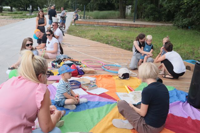 dzieci i dorośli siedzą na chuście animacyjnej, bawią się, malują