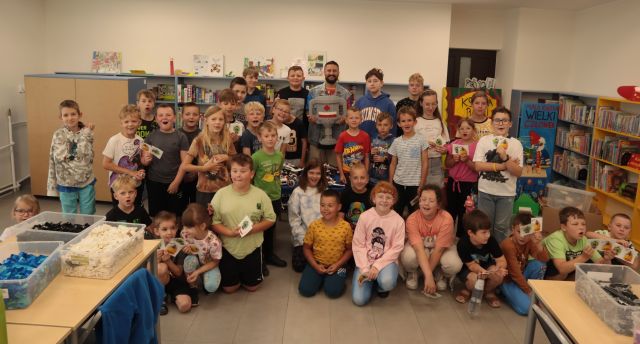 40 dzieci uczestniczącach w warsztatach z klockami Lego pozuje do zdjęcia z gościem