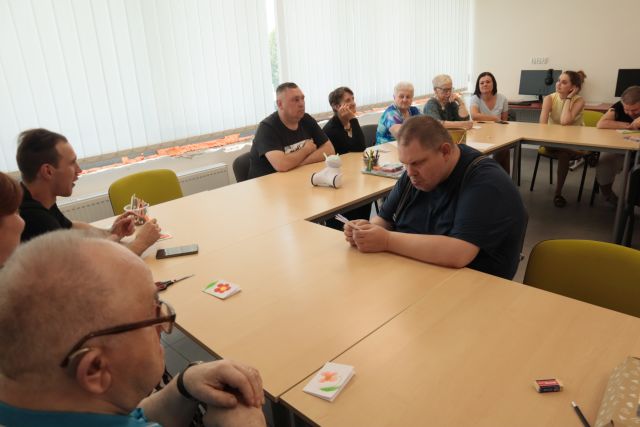 dorosłe osoby składają kartki metodą origami