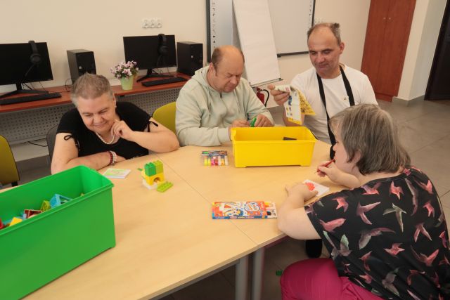 dorosłe osoby układają z klocków LEGO
