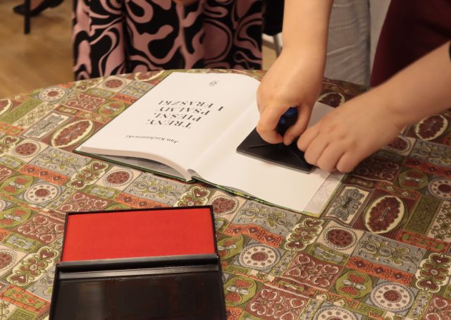 dłoń odciskająca pieczęć na książce