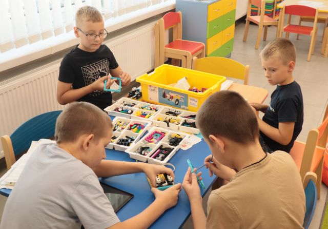 chłopcy przy stoliku budują z klocków LEGO