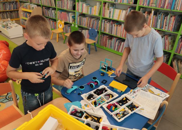 chłopcy przy stoliku budują z klocków LEGO