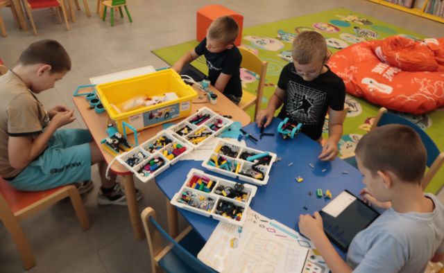 chłopcy przy stoliku budują z klocków LEGO