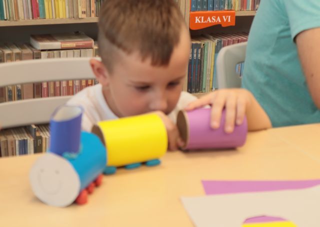 chłopiec robi pociąg z obklejonych kolorowym papierem rolek po papierze toaletowym