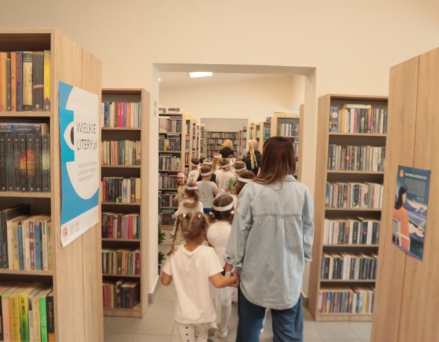 przedszkolaki pomiędzy regałami z książkami