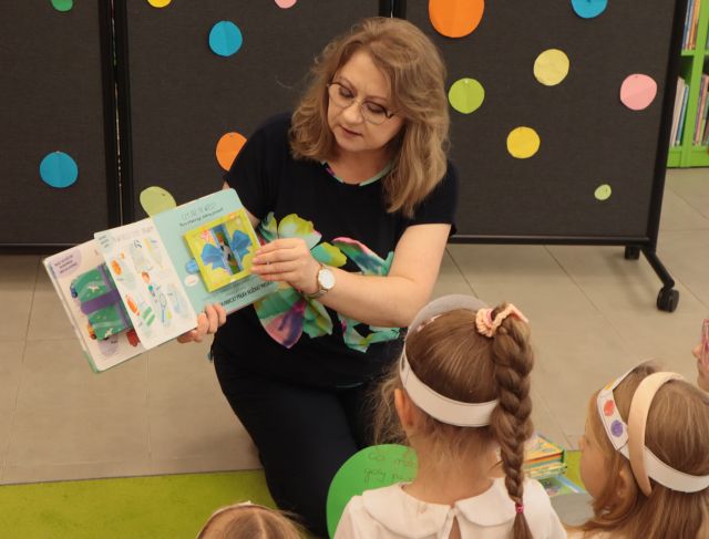 bibliotekarka pokazuje dzieciom książkę