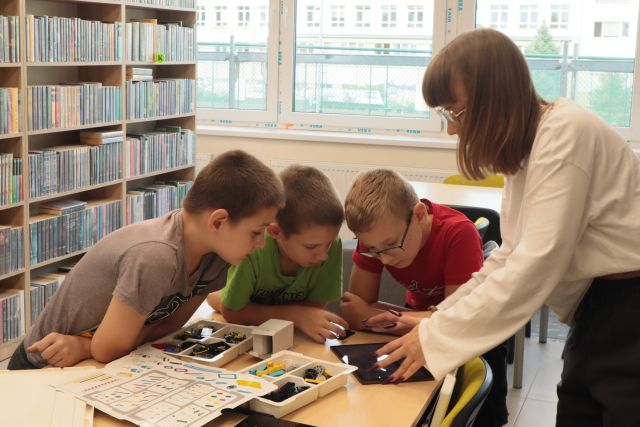 bibliotekarka pokazuje 3 chłopcom na tablecie