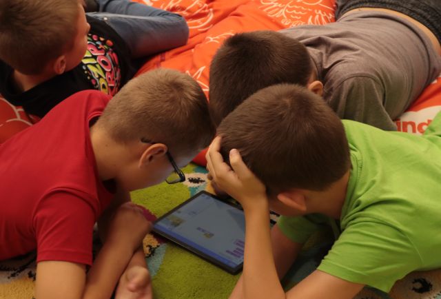 3 chłopców pochylonych nad tabletem