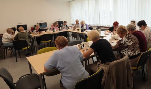 seniorki siedzą przy stołąch i notują na kartkach