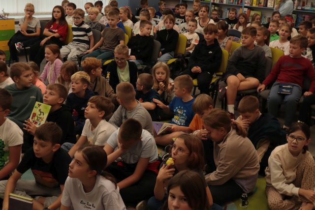 uczniowie siedzą na krzesłach i dywanie