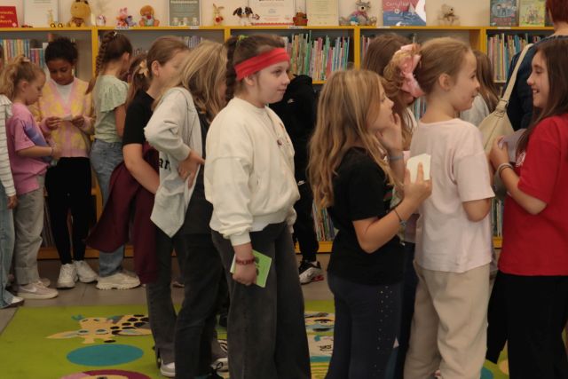 dzieci z książkami stoją w kolejce