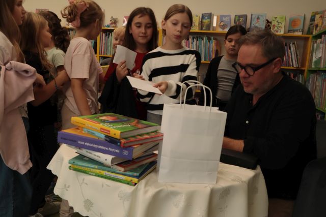 autor podpisuje książkę, przed nim stoją dzieci