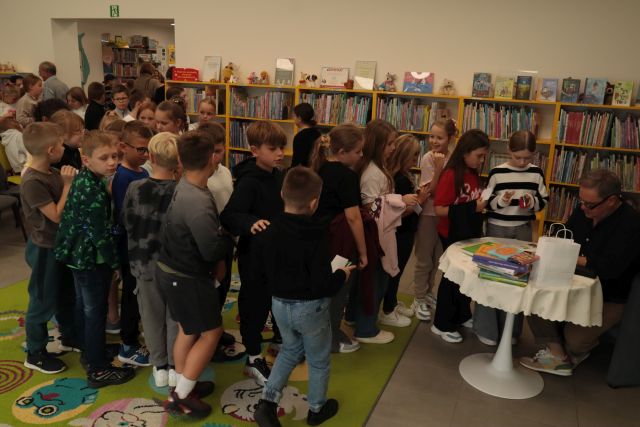 autor podpisuje książkę, przed nim stoją dzieci