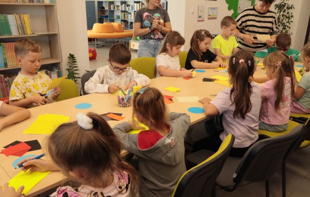 dzieci przy stołach wycinają z żółtych kartek