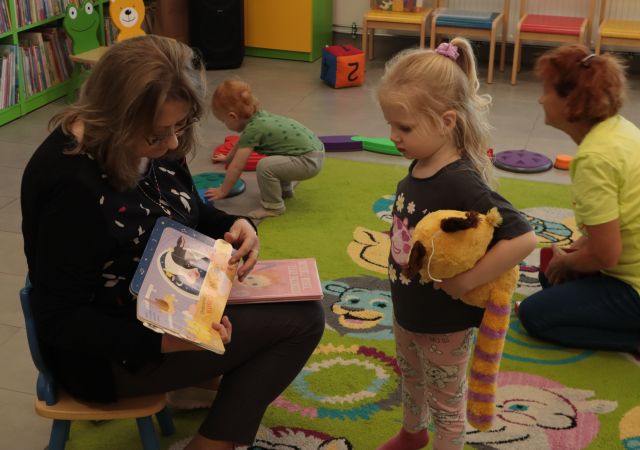 bibliotekarka pokazuje dziewczynce książkę