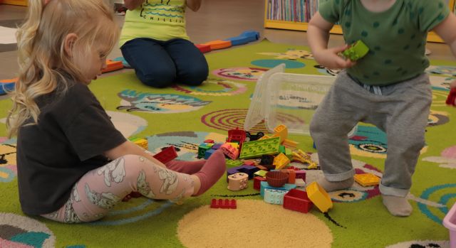 dzieci na dywanie układają klocki