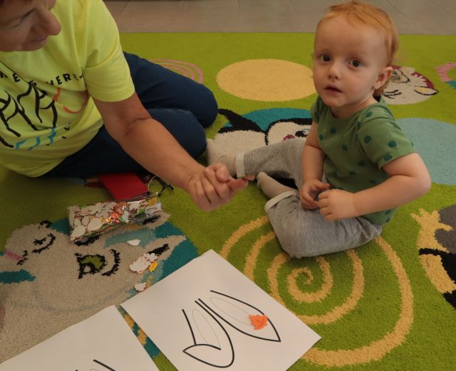 na dywanie siedzi dziecko z mamą, orzed nimi leży kartka z zarysowanymi oślimi uszami