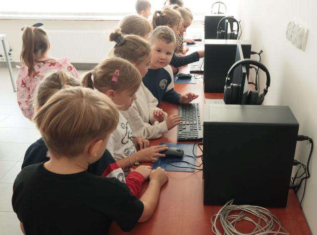 dzieci stoją przed komputerami