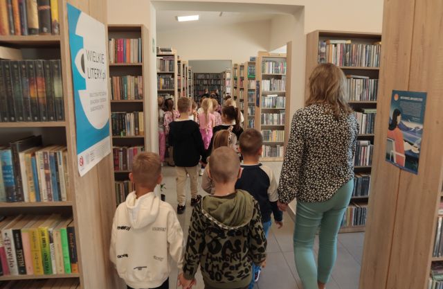 dzieci pomiędzy regałami z książkami