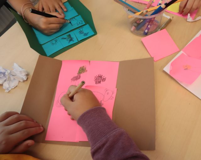 na zdjęciu dziecięca dłoń rysująca na różowej kartce