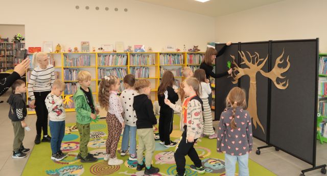 przedszkolaki stoją w kolejce do planszy z dużym drzewem 