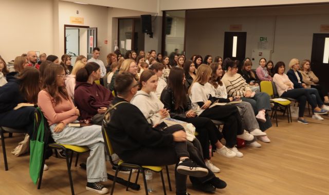 na zdjęciu publiczność siedząvca na krzesłach