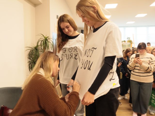 autorka podpisuje się na koszulkach dwóch dziewczyn