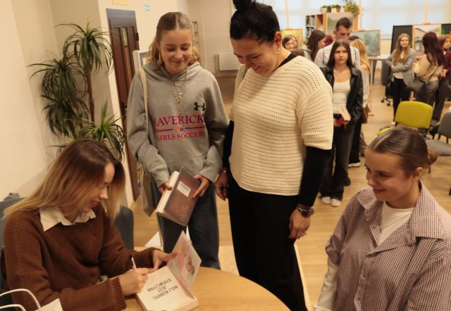 autorka podpisuje dwóm mkobietom książki