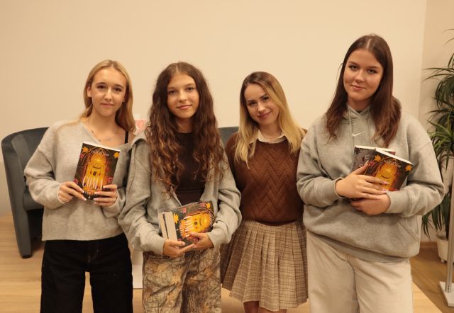 3 dziewczyny z książkami pozują do zdjęcia z autorką