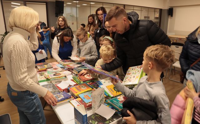 dzieci i dorośli przy stole z książkami