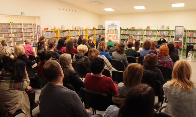 na zdjęciu uczestnicy spotkania siedzący na krzesłąch w sali bibliotecznej