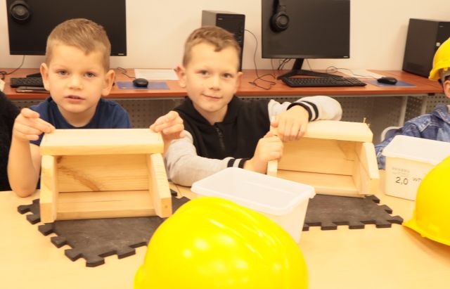 2 chłopców montuje drewniane skrzynki