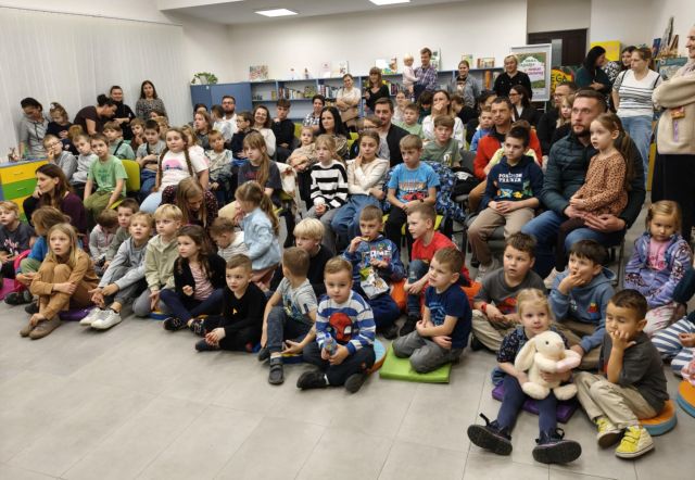 uczestnicy spotkania ze zwierzakami siedzą na podłodze i krzesłach