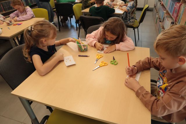przedszkolaki robią zakłądki do książki z papieru siedząc przy stoliku