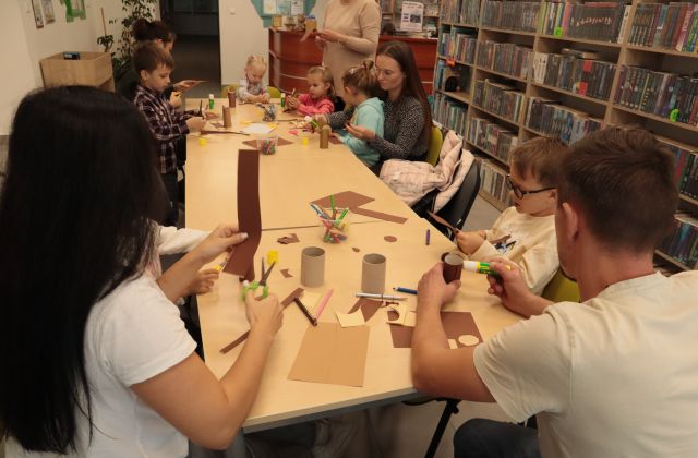 dzieci z rodzicami wycinają i kleją przy stołąch