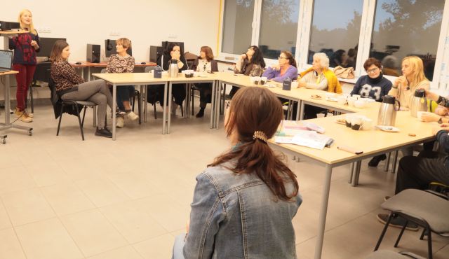 12 uczestników spotkania siedzi przy stołach ustawionych w literę L