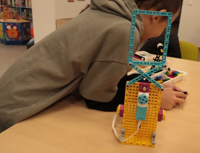 chłopiec oparty o stów z budowlą z klocków LEGO