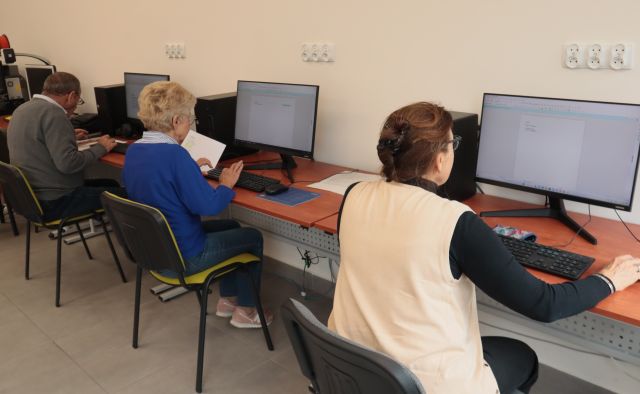 3 seniorów siedzi przy komputerach