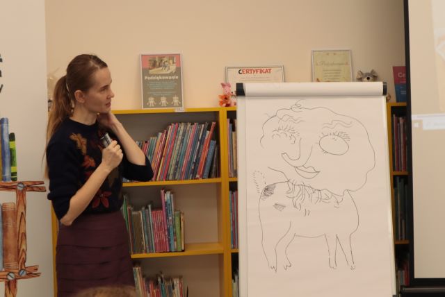 ilustratrka stoi przy flipcharcie z rysunkami