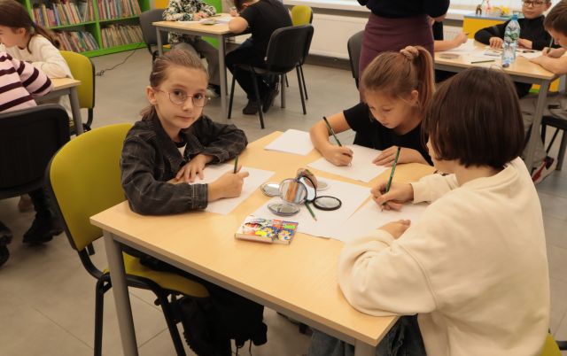 3 dziewczynki siedzą przy stoliku i rysują na kartkach