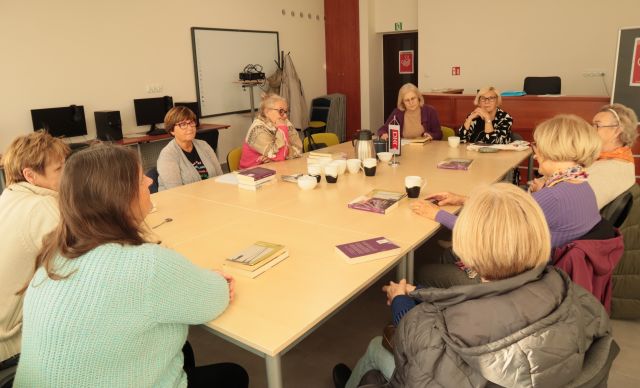 9 kobiet siedzi przy połączonych stołach