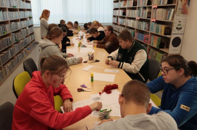 młodzież siedząca przy stołąch pisze na kartkach